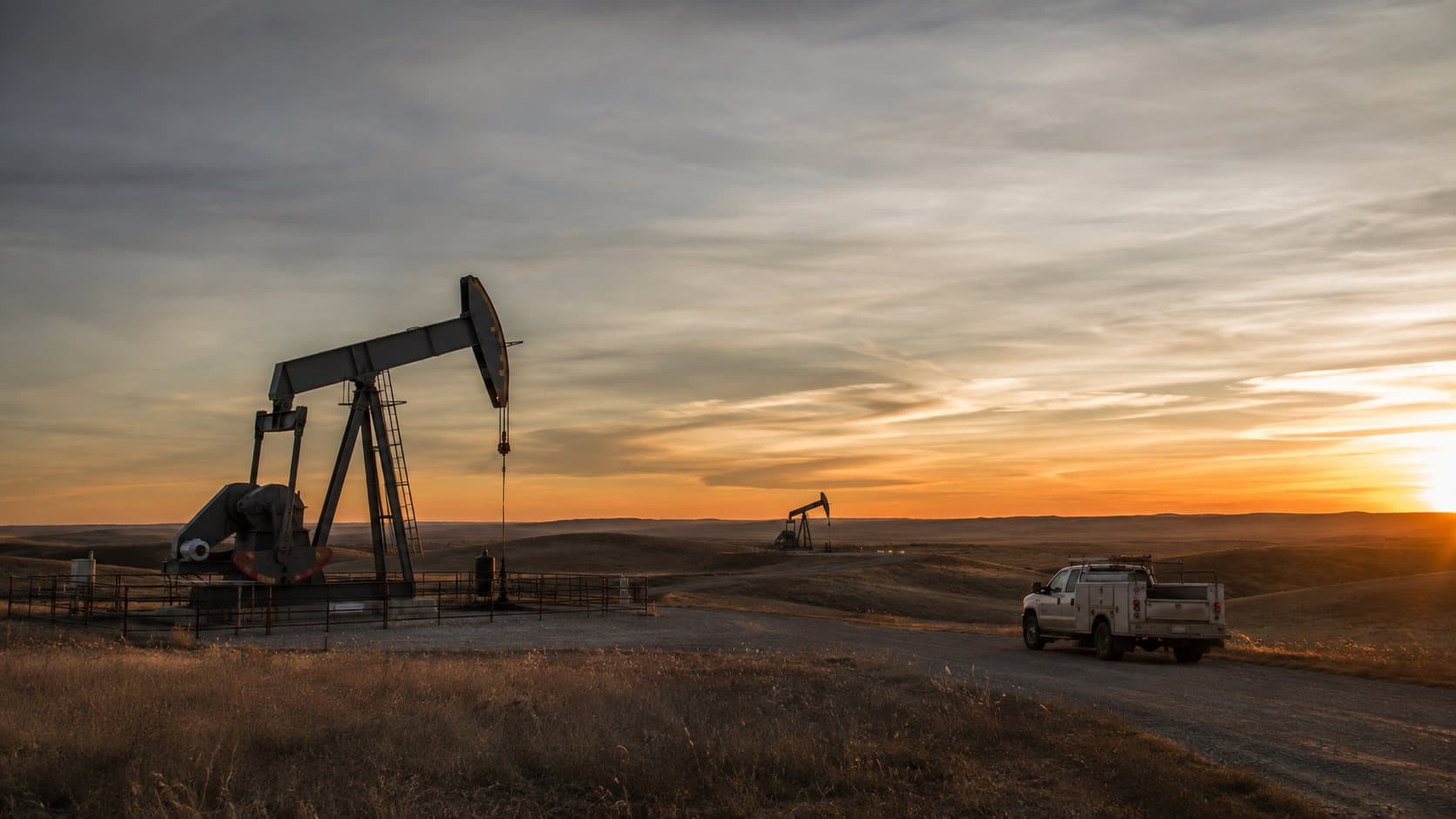 Pumpjacks on prairie farmland at sunset